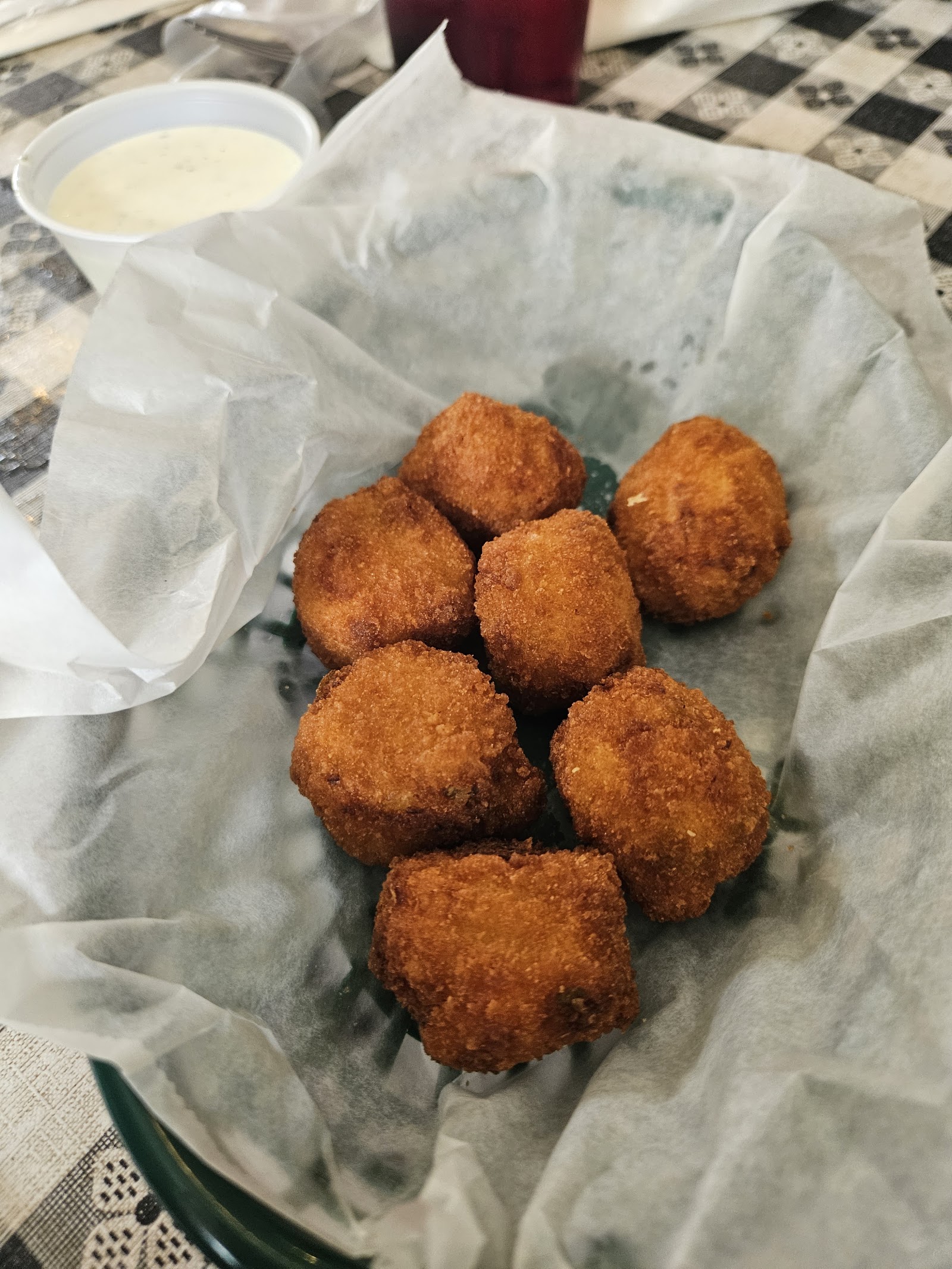 Basket of golden fried hush puppies with dipping sauce